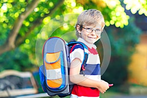 Little kid boy with school satchel on first day to school