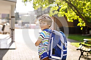 Little kid boy with school satchel on first day to school