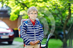 Little kid boy with school satchel on first day to school