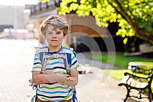 Little kid boy with school satchel on first day to school