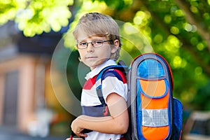 Little kid boy with school satchel on first day to school