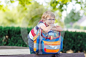 Little kid boy with school satchel on first day to school