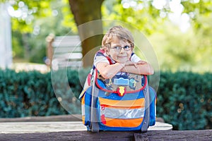 Little kid boy with school satchel on first day to school