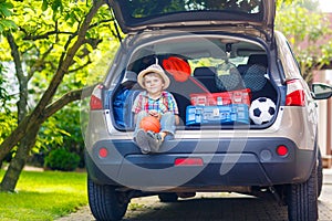 Little kid boy sitting in car trunk just before leaving for vaca