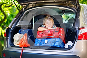 Little kid boy sitting in car trunk just before leaving for vaca