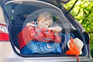 Little kid boy sitting in car trunk just before leaving for vaca