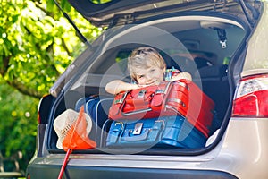 Little kid boy sitting in car trunk just before leaving for vaca