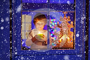 Little kid boy standing by window at Christmas