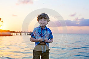 Little kid boy at sunset near ocean