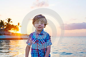 Little kid boy at sunset near ocean