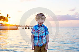 Little kid boy at sunset near ocean