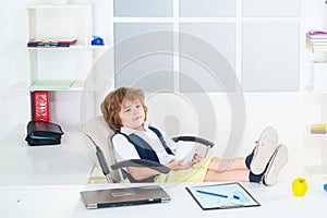 Little kid boy young businessman working at modern office. Marketing plan researching. Kid dreaming about businessman or