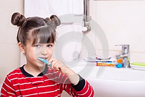 Little kid brushing her teeth in the bathroom. Child brush teeth.