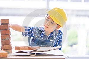 Little kid with construction wear working on brick work wall for future professional education concept