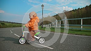Little kid crossing road on bike in slow motion. Focused boy riding on cycle.