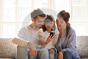 Little kid daughter holding cellphone enjoy using mobile app