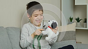 Little kid doctor listening to toy plush dog with stethoscope