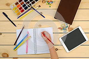 Little kid doing homework in notebook - top view