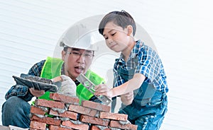 Little kid family with construction wear is learning to work on brickwork wall for future professional education concept