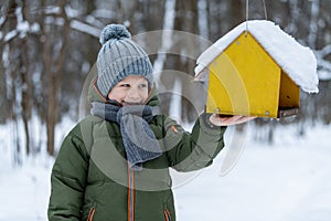 Little kid feeding birds in winter in the forest.