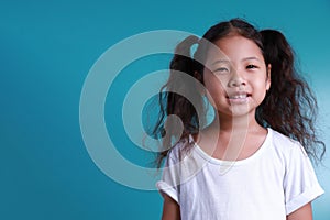 Little kid girl beautiful smile happiness portrait looking at the camera on green background with copy space