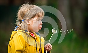 Little kid girl blowing on dandelion. Future generation. Windmills. Renewable energies and sustainable resources - wind