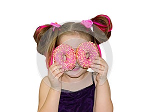 A little kid girl dabbles and plays with two fresh donuts before eating. A child holds donuts near his eyes and looks through the