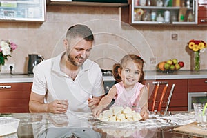 Little kid girl help man to cook lazy dumplings in light kitchen at table. Happy family dad, child daughter cooking food
