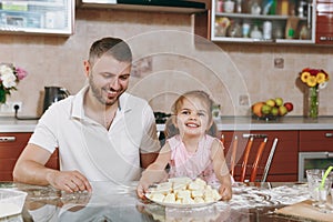 Little kid girl help man to cook lazy dumplings in light kitchen at table. Happy family dad, child daughter cooking food