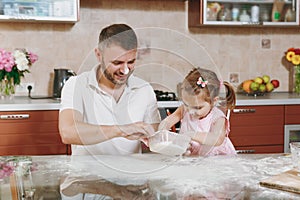 Little kid girl helps man to cook Christmas ginger cookies in kitchen at table. Happy family dad, child daughter cooking