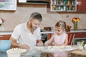 Little kid girl helps man to cook lazy dumplings, cutting dough at table. Happy family dad, child daughter cooking food