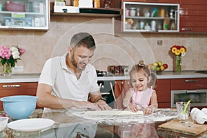 Little kid girl helps man to cook lazy dumplings, forming dough at table. Happy family dad, child daughter cooking food