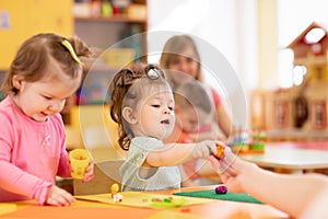 Little kid girl learning to use colorful play dough in kindergarten