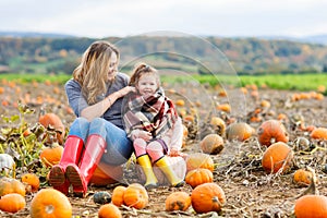 Little kid girl and mother having fun on pumkin field