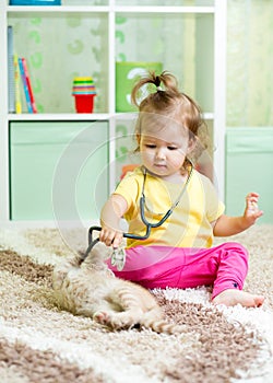 Little kid girl plays doctor with kitten
