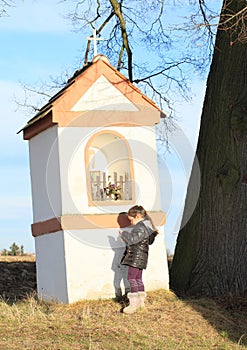 Little kid - girl praying by a chapel