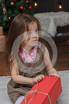 Little kid girl with the red christmas box gift at hands.