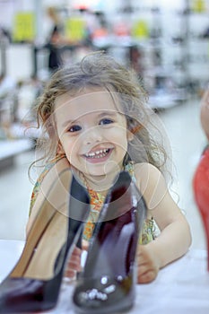 Little kid girl in a shoes store with the shoes on a shop-window.