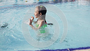 Little kid girl swim in a swimming pool clear water on summer resort