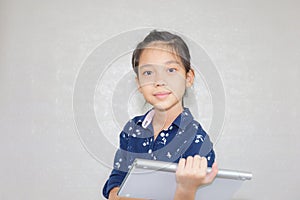 Little kid girl typing at wireless computer keyboard, Portrait of Happy child looking at camera with blurred background