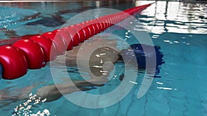 Little kid going underwater near a red plastic pool divider