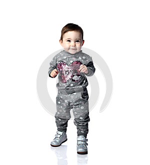 Little kid in gray suit with snowflakes print and boots. She is smiling, stomping on floor, isolated on white background. Close up