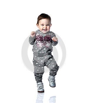 Little kid in gray suit with snowflakes print and boots. She is smiling, stomping on floor, isolated on white background. Close up