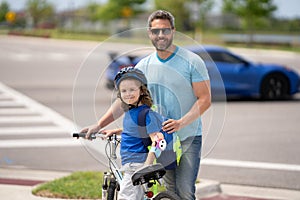 Little kid learning to ride bicycle with father on on summer holiday. Father teaching son cycling. Father and son