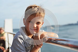 Little kid looking at the sea from the railing of a cruise