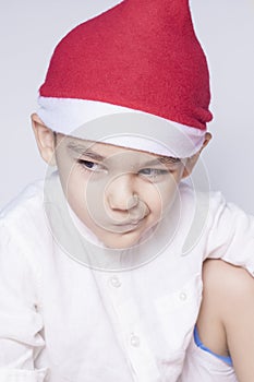 A little kid making a funny annoyed face. Annoyed Christmas Boy in Santa Hat. A really serious and handsome kid