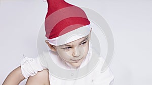 A little kid making a funny annoyed face. Annoyed Christmas Boy in Santa Hat. A really serious and handsome kid