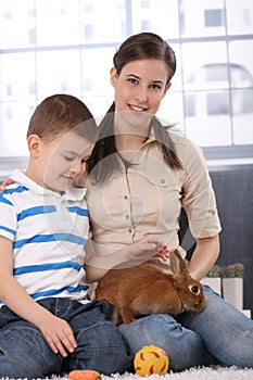 Little kid with mum caressing rabbit pet