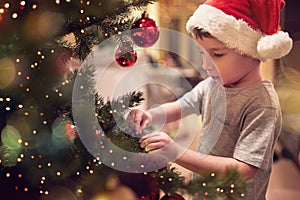 A little kid ornamenting a Christmas tree at home. Together, New Year, family, celebration