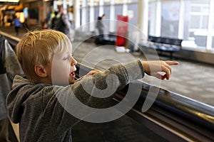 Little Kid on People Mover at Airport Pointing out Window